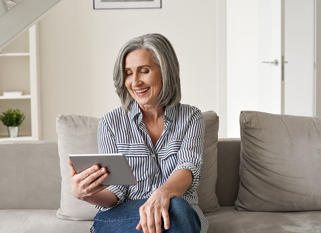 Service Center - Cheerful Senior Woman Reads Her Tablet at Home